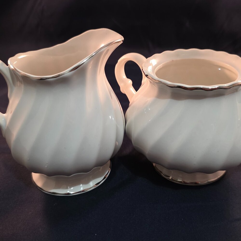 White fluted ceramic creamer and sugar bowl set with silver trim.